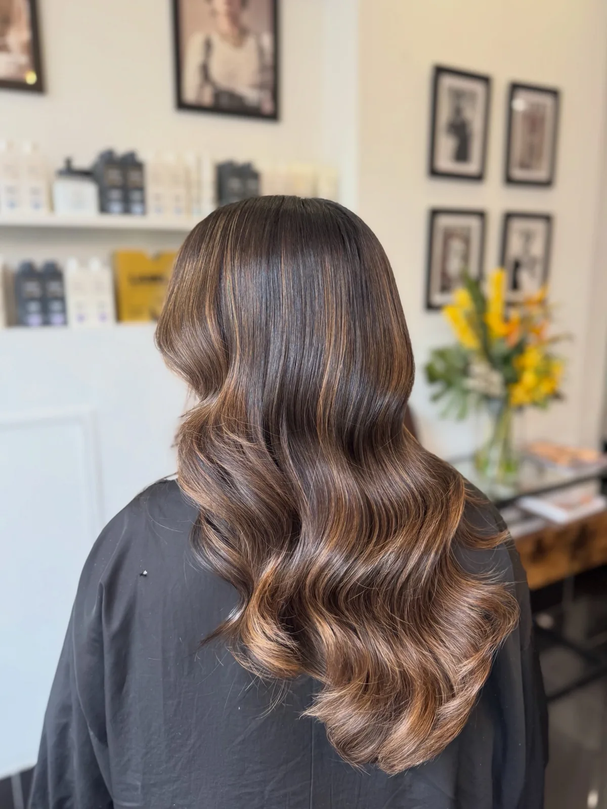 Long brunette hair with a soft caramel balayage, finished in glossy waves