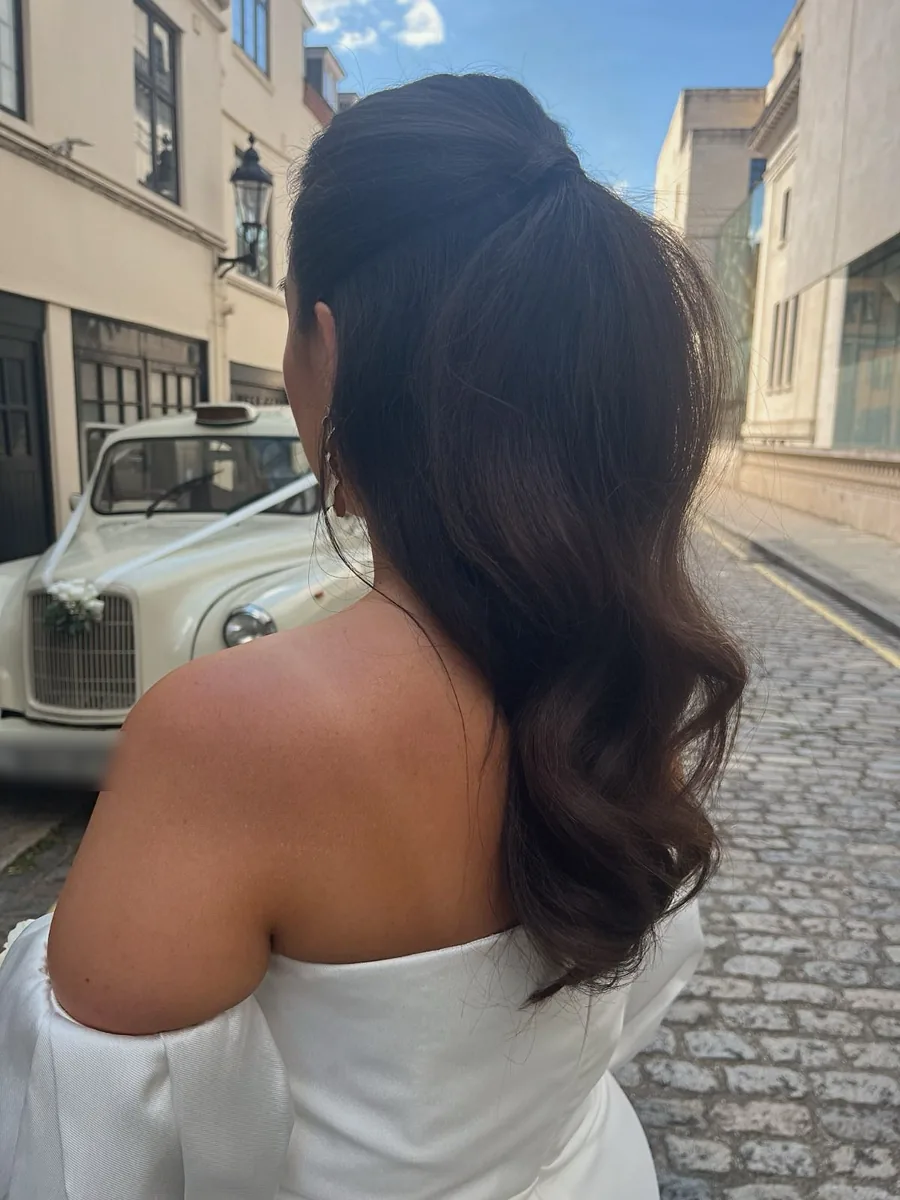 A bride with a glossy half-up Hollywood wave, styled by Libby, on a cobbled London street